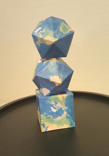 Three folded paper globes stacked — dodecahedron, icosahedron and cube